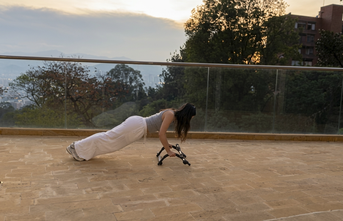 Tatiana en posición de plancha sobre una terraza, con la ciudad y las montañas al atardecer al fondo.