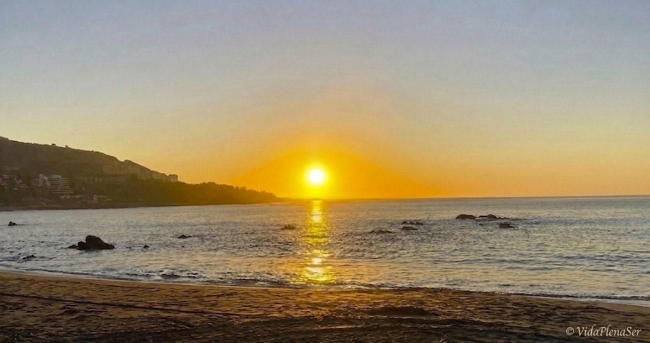 Atardecer dorado sobre el mar y la playa.